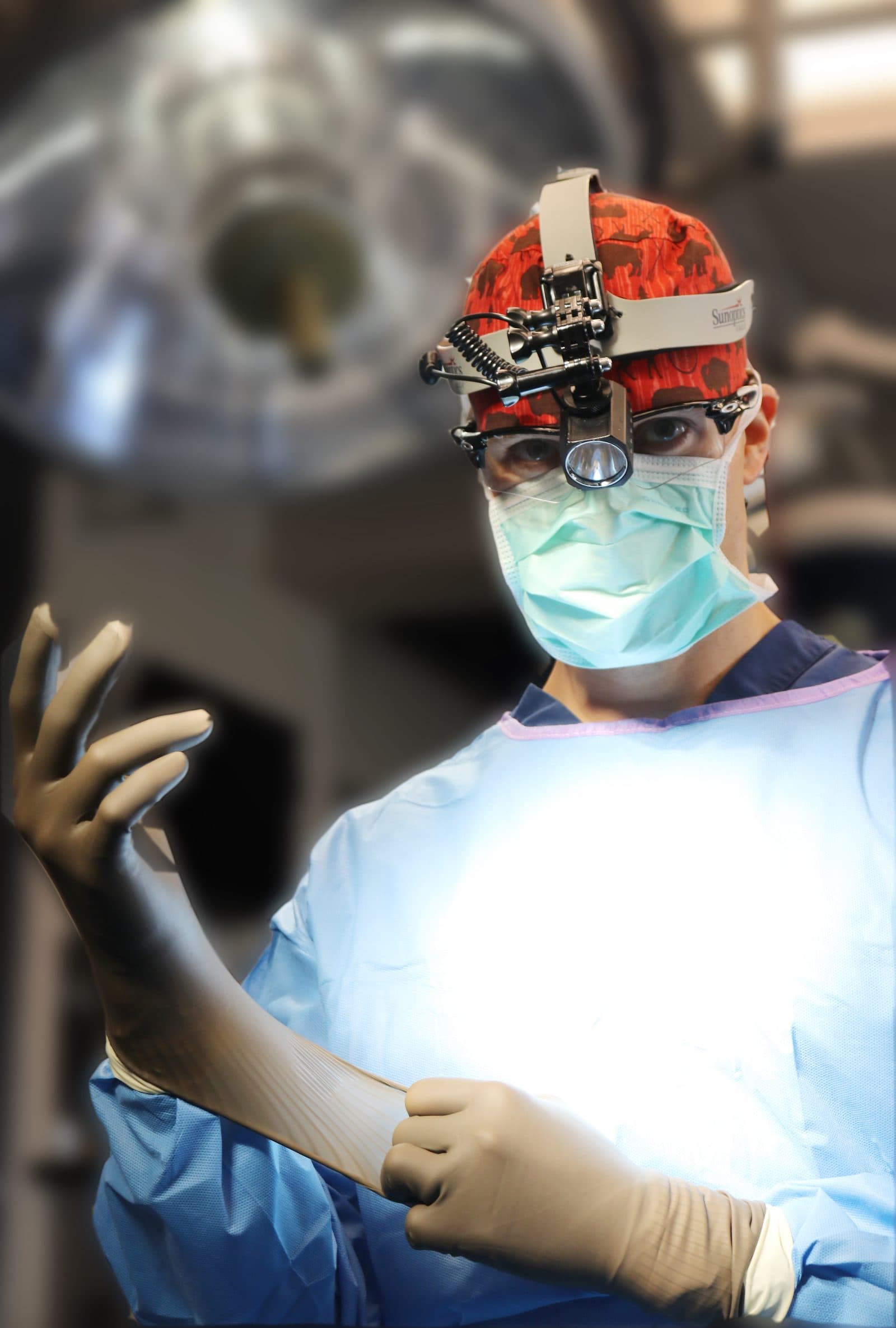 Dr. Smith gowning and gloving under the surgical lights